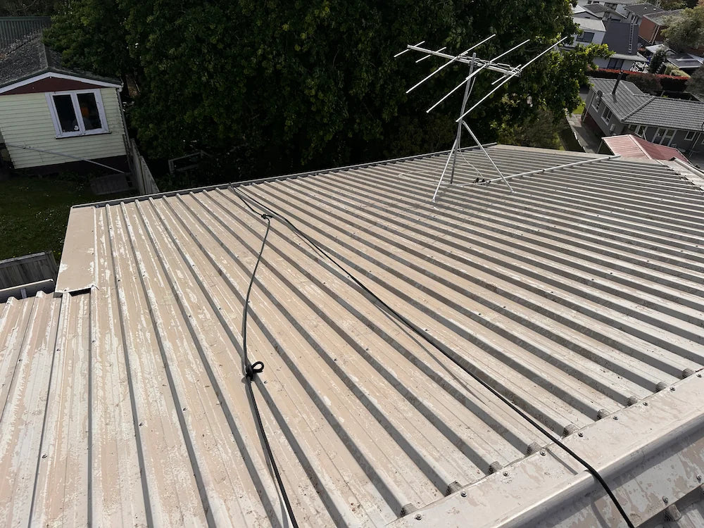 Corrugated metal roof is cleared of moss, dirt, and debris after professional pressure washing, revealing a clean surface.