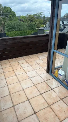 Tile patio deck showing clean, bright tiles free of mildew and grime alongside a dark wooden balustrade, restored.