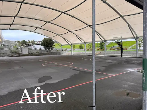 Cleaned concrete court after pressure washing. Bright clean lines and cleared surface beneath the shade sail.