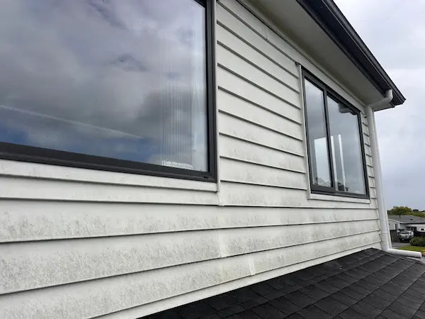 Close-up of weatherboards caked in dirt and mildew before professional pressure washing restores the home's exterior.