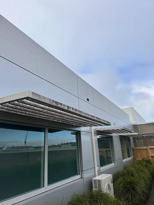 Commercial building facade with aluminium sunshade showing dirt and streaks before exterior cleaning.